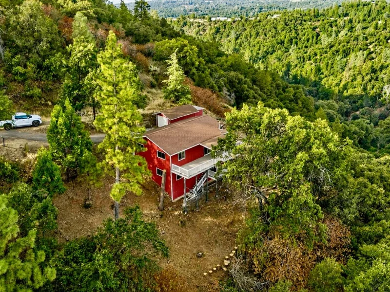 Red two-story home among pine trees at 20336 Stardust Way, Tuolumne, California